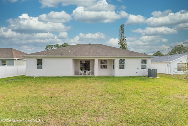 rear view of property with central AC unit, a patio, and a lawn