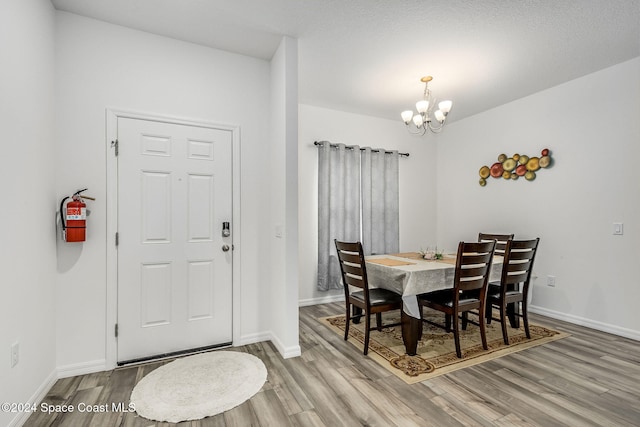 dining space with light hardwood / wood-style flooring, a notable chandelier, and a textured ceiling