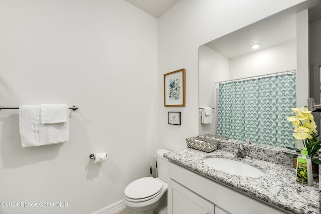 bathroom with curtained shower, vanity, and toilet