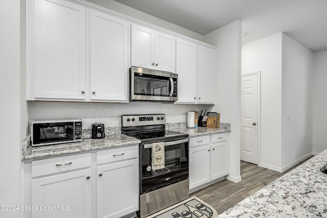 kitchen featuring white cabinets, light stone counters, light hardwood / wood-style flooring, and appliances with stainless steel finishes