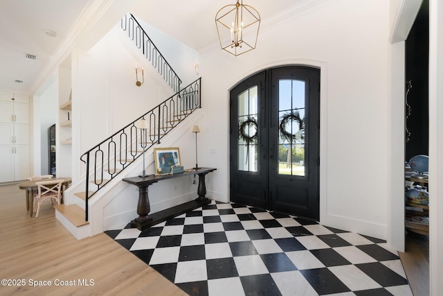 entrance foyer featuring french doors, dark hardwood / wood-style flooring, crown molding, and a chandelier