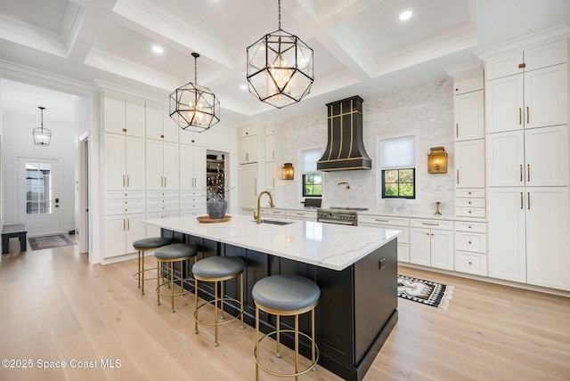 kitchen with decorative light fixtures, custom range hood, white cabinets, and a spacious island