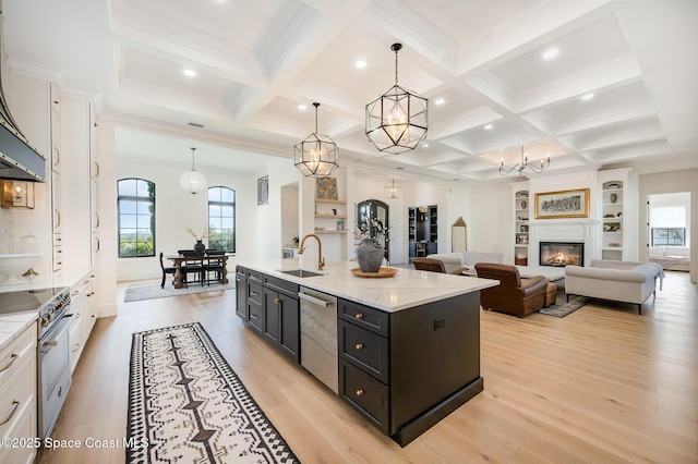 kitchen with stainless steel appliances, a kitchen island with sink, hanging light fixtures, and white cabinets