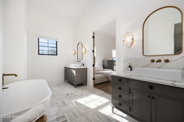 bathroom featuring ornamental molding, a bath, and vanity