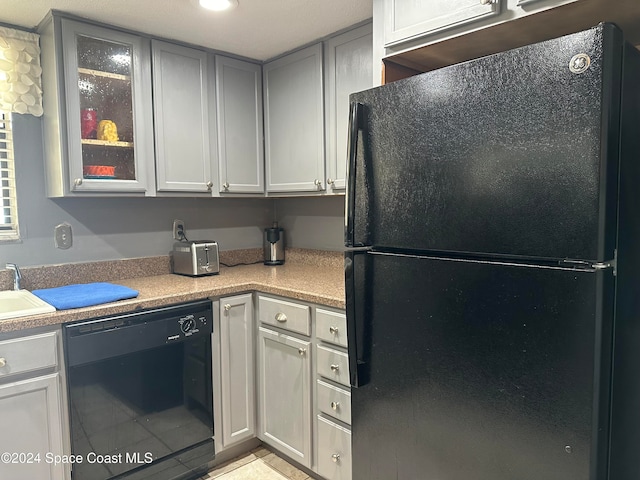 kitchen with gray cabinets, black appliances, and sink