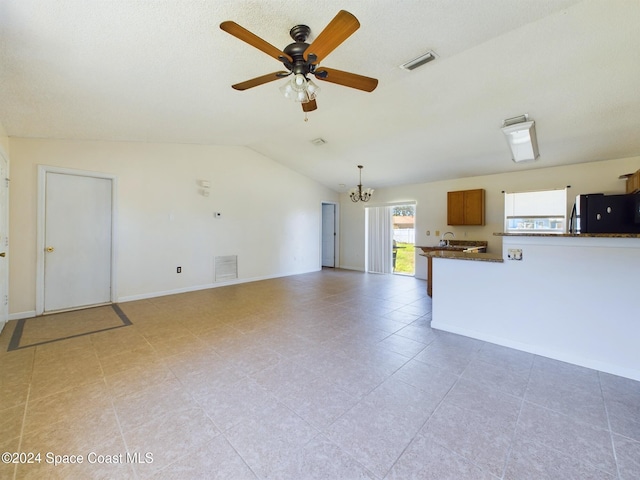 unfurnished living room with ceiling fan with notable chandelier and lofted ceiling