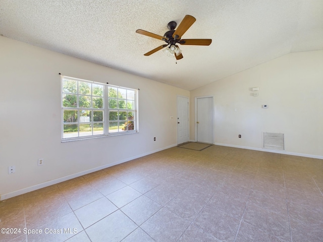 tiled spare room featuring lofted ceiling, a textured ceiling, and ceiling fan