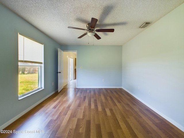 spare room featuring dark wood-type flooring, a textured ceiling, and ceiling fan