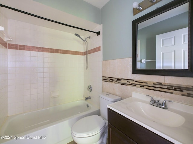 full bathroom featuring tile walls, vanity, toilet, and tiled shower / bath