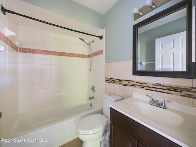 full bathroom with tile walls, vanity, tiled shower / bath combo, and toilet