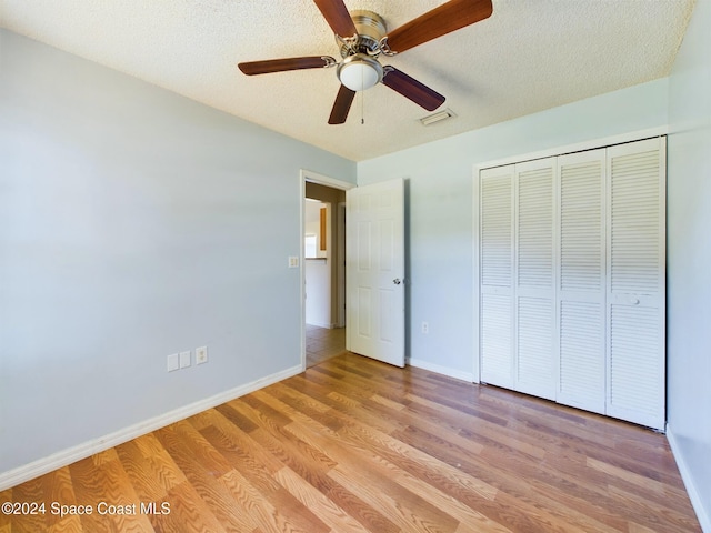 unfurnished bedroom featuring a textured ceiling, light hardwood / wood-style flooring, ceiling fan, and a closet