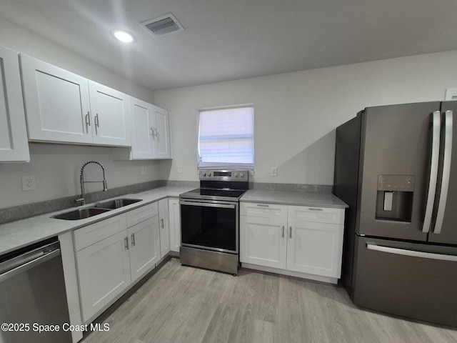 kitchen featuring stainless steel appliances, sink, white cabinets, and light hardwood / wood-style flooring