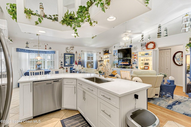 kitchen with stainless steel appliances, white cabinetry, decorative light fixtures, sink, and light hardwood / wood-style floors