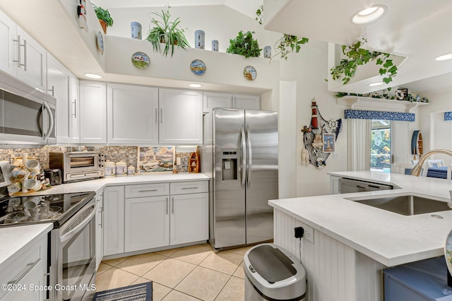 kitchen with appliances with stainless steel finishes, light tile patterned floors, decorative backsplash, sink, and white cabinets