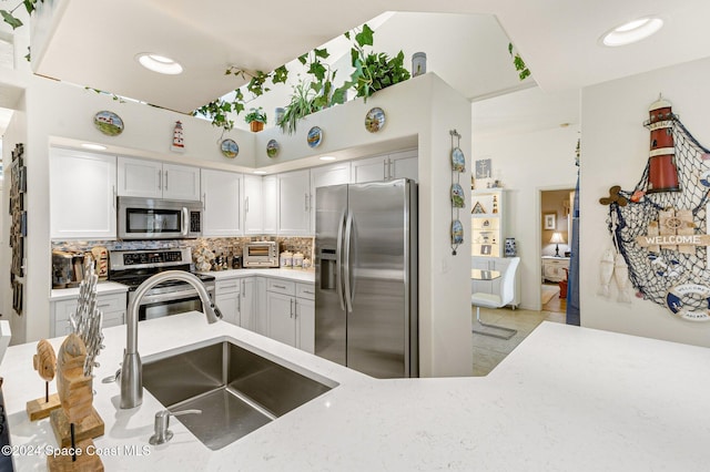 kitchen featuring stainless steel appliances, decorative backsplash, sink, light tile patterned flooring, and white cabinetry