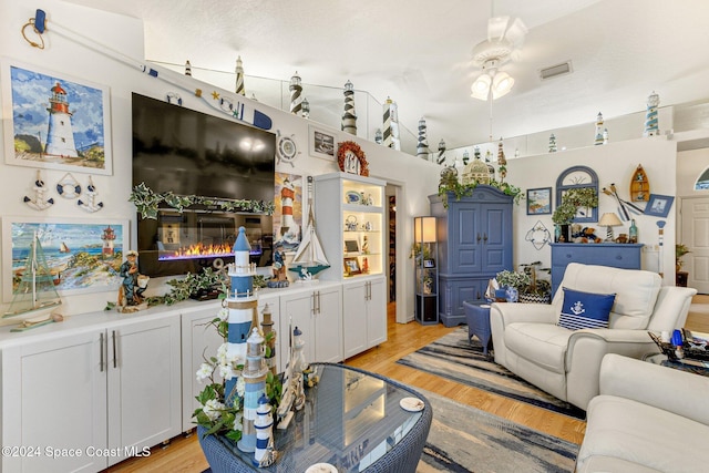 living room featuring a textured ceiling, light hardwood / wood-style flooring, and ceiling fan