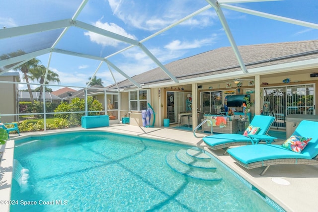 view of pool with pool water feature, glass enclosure, ceiling fan, and a patio area