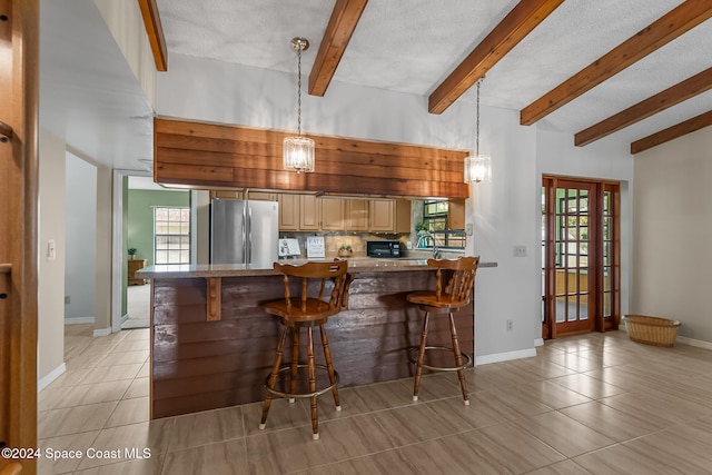 kitchen featuring a wealth of natural light, stainless steel refrigerator, a textured ceiling, and a breakfast bar