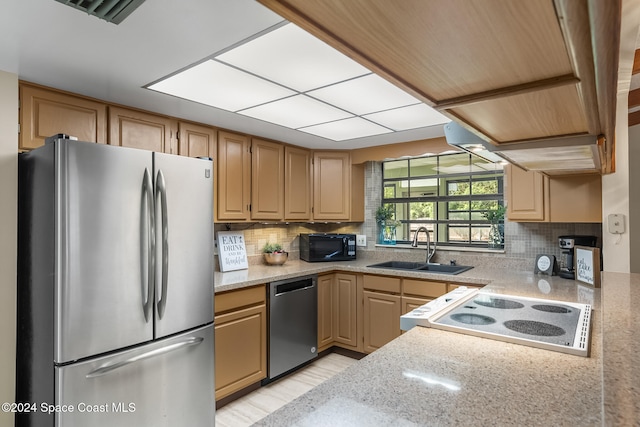 kitchen with appliances with stainless steel finishes, light stone countertops, decorative backsplash, sink, and light hardwood / wood-style floors