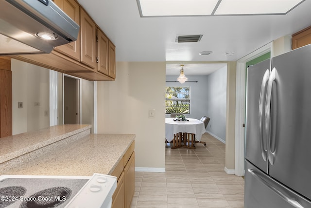 kitchen with pendant lighting, ventilation hood, and stainless steel refrigerator