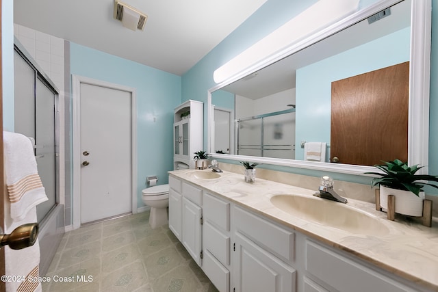 full bathroom featuring enclosed tub / shower combo, vanity, and toilet