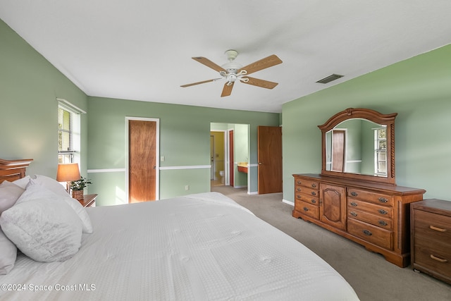 carpeted bedroom with ensuite bath and ceiling fan