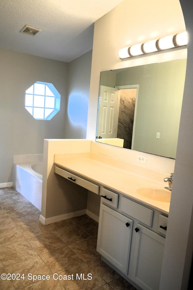 bathroom featuring vanity, a tub, tile patterned floors, and a textured ceiling