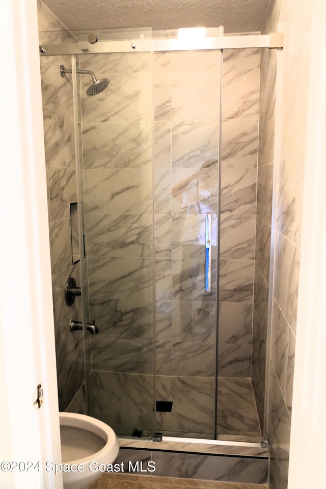 bathroom featuring walk in shower, toilet, and a textured ceiling