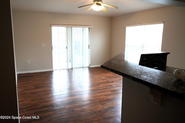 spare room with a healthy amount of sunlight, dark hardwood / wood-style floors, and ceiling fan