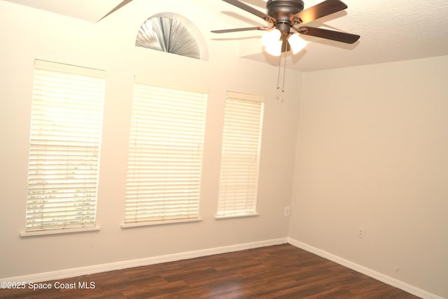 spare room with ceiling fan, baseboards, and dark wood-type flooring