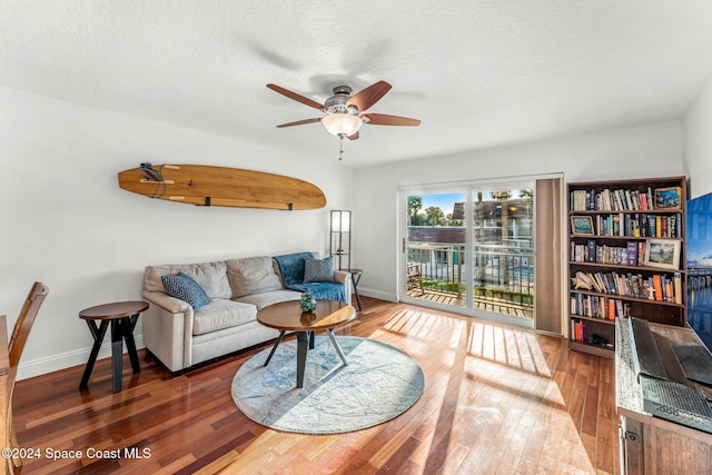 living room featuring dark hardwood / wood-style flooring, a textured ceiling, and ceiling fan