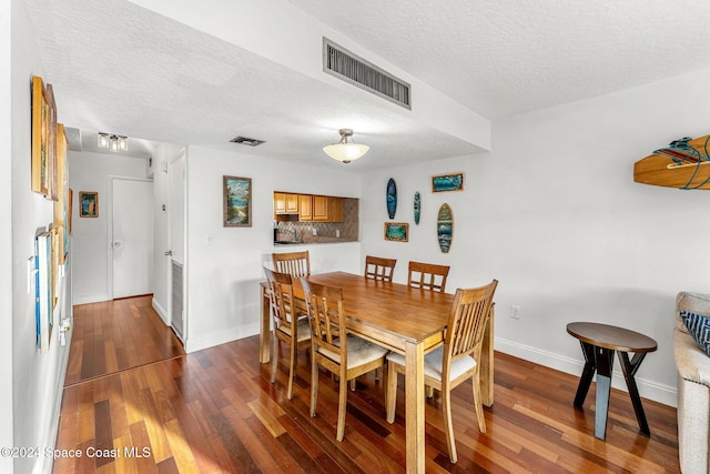 dining room featuring dark hardwood / wood-style flooring and a textured ceiling