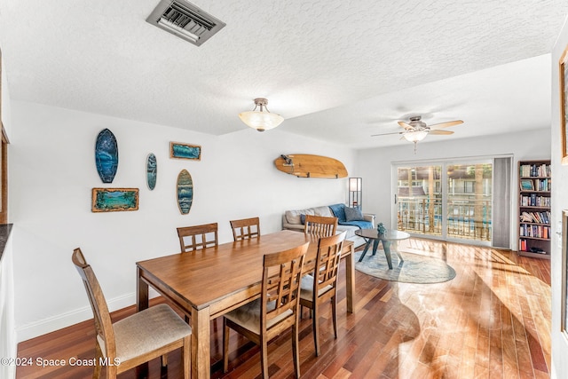 dining area with ceiling fan, wood-type flooring, and a textured ceiling