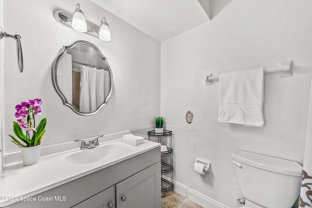 bathroom with tile patterned flooring, vanity, and toilet