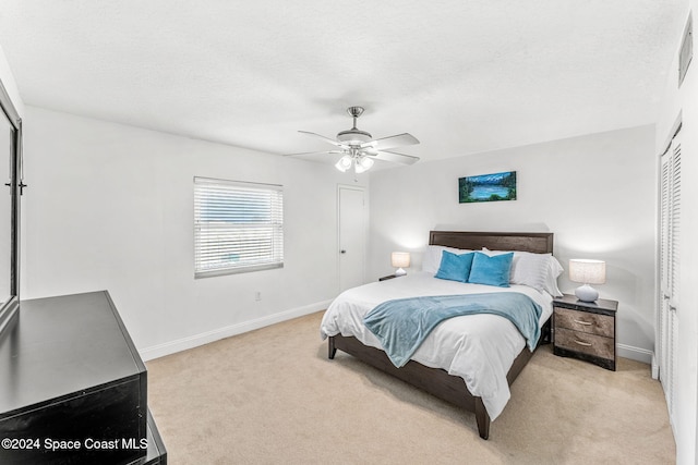 carpeted bedroom with a closet, a textured ceiling, and ceiling fan