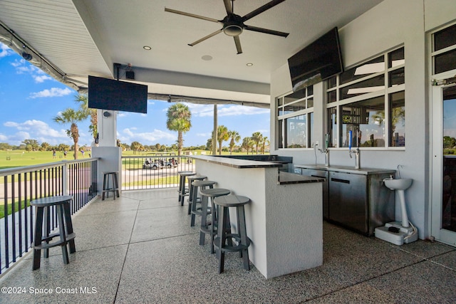 view of patio with ceiling fan and a bar