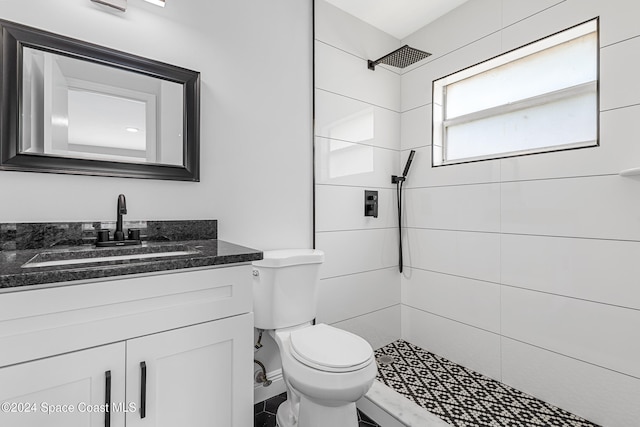 bathroom featuring a tile shower, vanity, and toilet