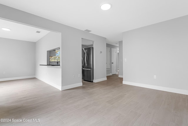 unfurnished living room featuring light wood-type flooring and sink