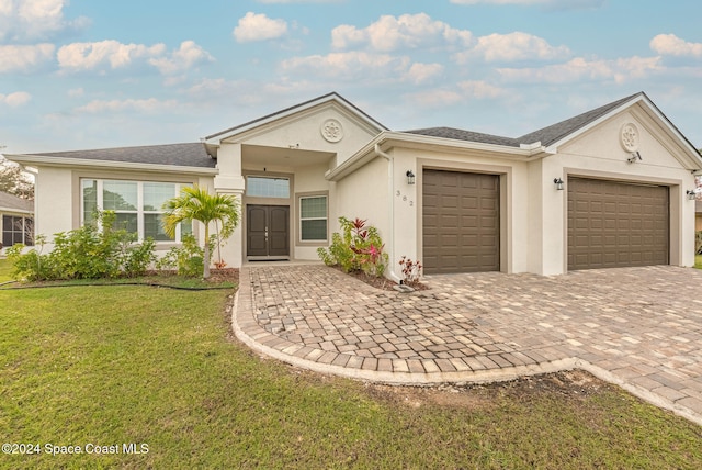 ranch-style home with a garage and a front lawn