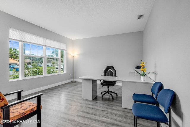 office area with light hardwood / wood-style flooring and a textured ceiling