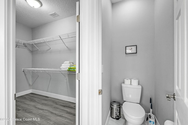 bathroom featuring hardwood / wood-style floors, a textured ceiling, and toilet