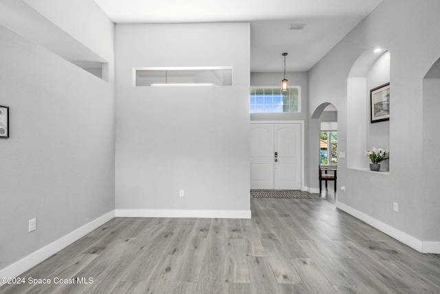 entryway featuring light hardwood / wood-style floors and a towering ceiling