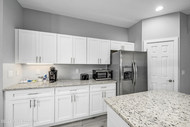 kitchen with light stone countertops, appliances with stainless steel finishes, and white cabinets