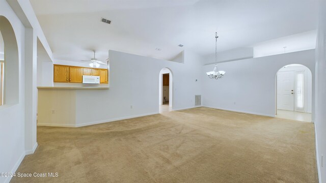 unfurnished living room with ceiling fan with notable chandelier, lofted ceiling, and light carpet