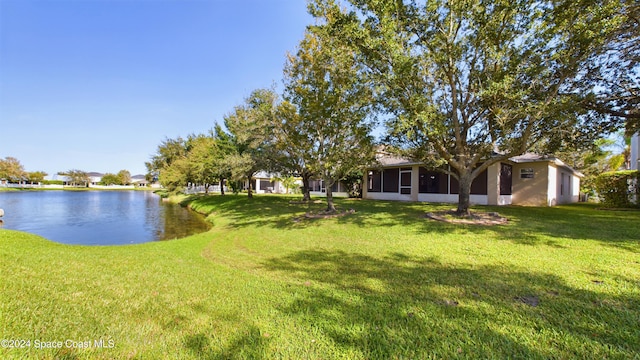 view of yard with a sunroom and a water view