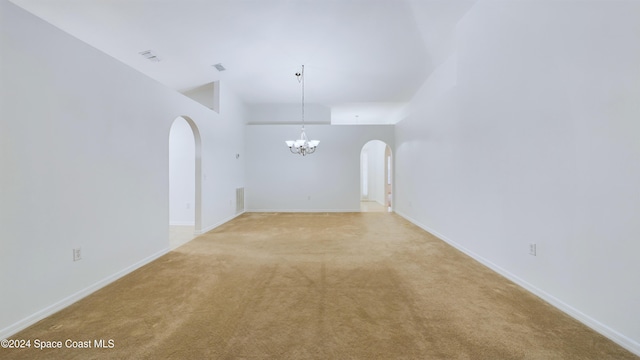 carpeted spare room featuring an inviting chandelier