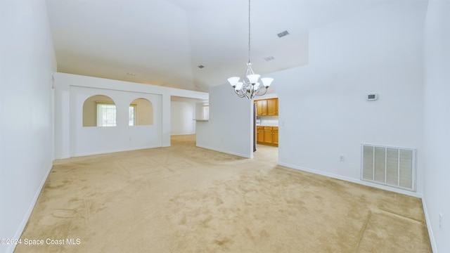 unfurnished living room with a high ceiling, light colored carpet, and a notable chandelier