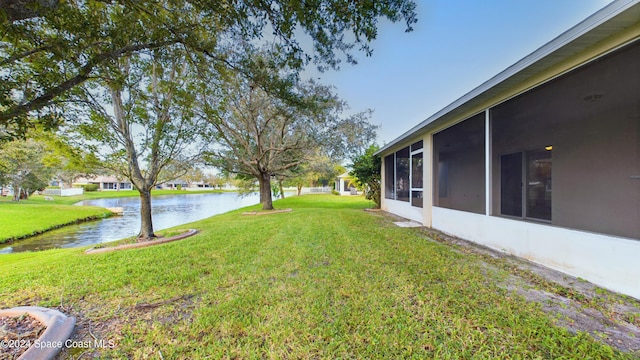 view of yard with a sunroom and a water view