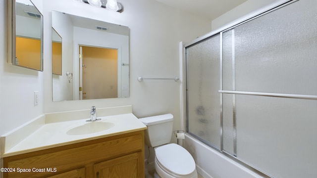 full bathroom with toilet, bath / shower combo with glass door, and vanity