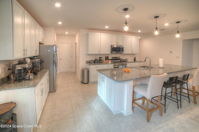 kitchen with stainless steel appliances, hanging light fixtures, white cabinets, and light stone counters